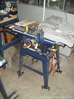 Full view of Mastercraft 10-inch table saw with metal stand and caster wheels, placed in workshop environment.