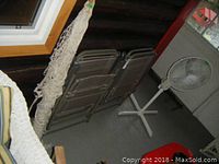 Photo showing the four folded lawn chairs and knotted rope hammock hanging nearby on the porch floor.