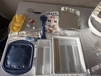 Overall lot showing utensils, trays, pans, blue lid, organizer trays and chopsticks