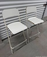 Front view of two white folding bar stools