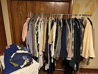 Full garment rack with assorted shirts, jackets, pants and folded items