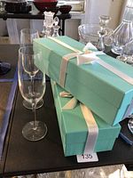 Two clear crystal flutes standing beside two Tiffany blue boxes with white satin ribbons