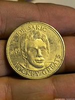 Obverse showing raised portrait of Joe Sakic, No.19 and HOCKEY GREATS legend