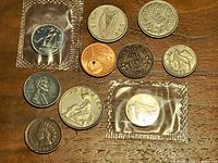 Overview of obverse faces of assorted world coins, showing two packaged pieces and nine loose pieces
