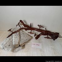 Overall view of carved wood branch with birds and folded crocheted throw
