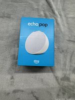 Front of blue Amazon Echo Pop box showing product image