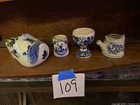 Four miniature Delft blue and white porcelain pieces lined on shelf