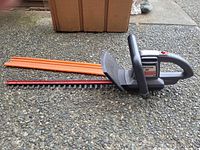Full view of Craftsman electric hedge trimmer with orange scabbard attached