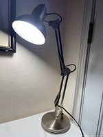 Lamp illuminated, showing adjustable arms and shade