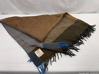 Folded woven wool plaid blanket showing color blocks and fringe