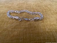 Full view of silver bracelet laid flat showing link style and clasp