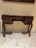 Front view of French Provincial console table showing four drawers, cabriole legs, carved apron