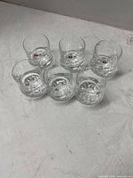 Top view of six clear Iittala cordial glasses showing bubble bases and logo decals