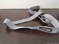 Gray fabric loop resistance band coiled on table showing texture and logo patch