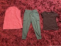 Full view of all three clothing items laid out (black T-shirt, green joggers, coral sleeveless top)