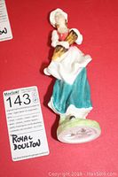 Royal Doulton figurine Lizzie HN 2749 laying on red surface with visible markings on base.