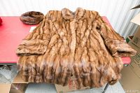Light mahogany mink coat with collar and folded sleeves, laid flat with mink beret on the side.