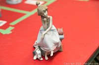 Three-quarter front view of figurine showing girl seated with telephone handset and Dalmatian at her feet