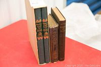 Four antique and vintage books: two green Book of the Month Club editions of Jane Eyre and Wuthering Heights standing in slipcase, a blue and gold decorated hardcover of The Pilgrims Progress, and a brown hardcover Painter Gilder and Varnisher book.