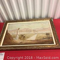 Framed antique painting viewed at an angle showing the entire artwork, the woman overlooking a landscape with mountains and palm trees.