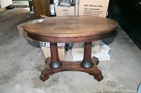 Front view of oval walnut table showing top and dual pedestal base