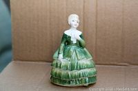 Front view of the Royal Doulton figurine 'Belle' in a green dress, showing detailed facial features and dress tiers.