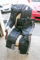 Two pairs of black and gray Spyder ski pants displayed on a chair and draped over it outdoors showing their full length and details