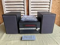 Front view of mini stereo system showing main unit, both speakers, remote and cables
