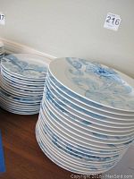Stacks of large dinner plates and smaller appetizer plates showing blue floral and scroll pattern on white ceramic.