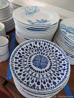 Stack of white salad plates with blue floral designs and a front stack of blue and white patterned bowls.