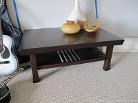 Full front view of rectangular dark wood coffee table with decorative items on top, showing overall size and design.