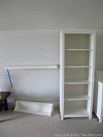 Photo showing the floating shelf mounted on the wall, the wood shelf with curved front on the floor, and the tall white bookcase standing upright.