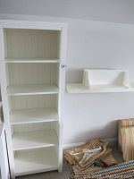 Tall white wooden bookcase with five shelves and paneled back.