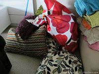Pile of assorted pillows and Fatboy bean bag chair on floor.