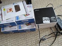 VuPoint Photo Cube printer with 4 packs of photo paper stacked, showing boxes and user manual on top.