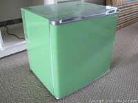 Mini fridge exterior side view showing bright green color and silver handle on top front.