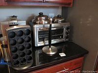 Countertop arrangement of all items: toaster oven, coffee machine, pod holder, canister, paper towel holder, pot lids.