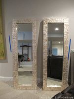 Two mirrors standing upright side by side against a wall