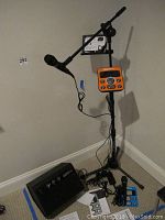 Full setup showing microphone on stand, orange control module, speaker on floor and connecting cables