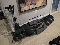 Full view of Samsonite golf carry bag laid on floor beside Tommy Armoire golf caddy showing all components