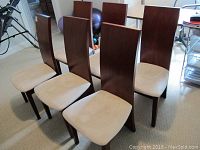 Six dark wood dining chairs with light beige upholstered seats arranged in two rows; seats show noticeable stains and legs have minor chips.