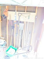 Wide view of gardening tools hung on pegboard wall and green Scott Turf Builder spreader with bags of product