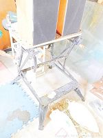 Full view of metal collapsible work bench with black paint showing some wear and structural design visible.