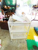 Plastic shelving unit showing perforated basket shelves on casters in a garage setting.