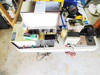 Overview photo of the vintage electronic testers and accessories on a table including the BK Precision voltmeter, 24V battery, fuses, and vacuum tube boxes.