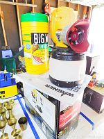 Yellow Wagner Power Painter Plus paint sprayer with attached paint container on top of its box next to a container of cleaning wipes.