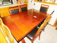 Top view of the rectangular wood dining table with black cushioned chairs around it.