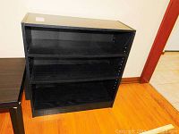 Oblique photo showing front and side of the black faux wood bookcase with adjustable shelves.