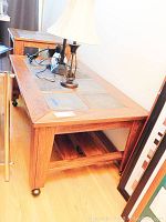 Overview of wooden table with slate tile inset top, showing side and leg design with caster wheels