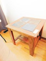 Full view of wood and slate side table showing four slate tiles inset into wooden top frame and wooden leg structure.